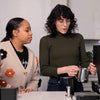 One person teaching another how to steam milk